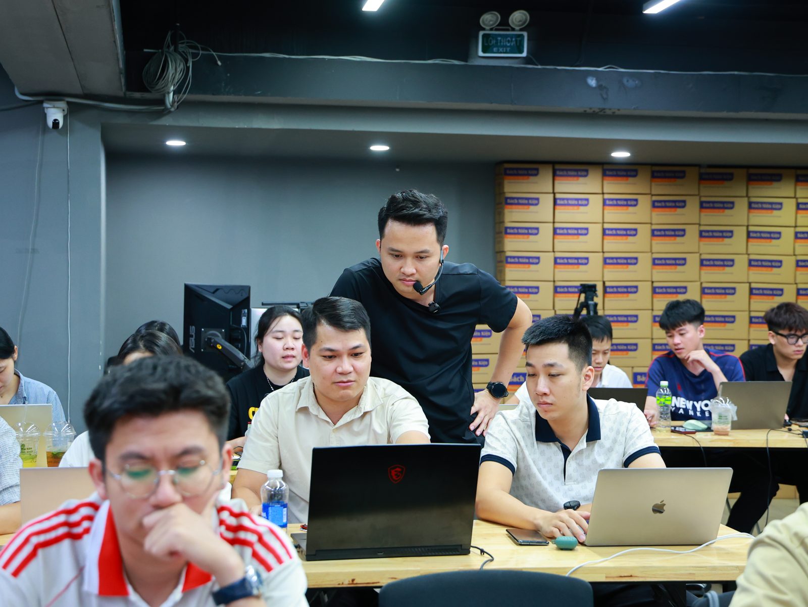 Phúc BANI cúi xuống màn hình hướng dẫn một nhân viên